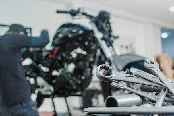 Clés et douilles au premier plan, un mécanicien travaille sur une moto derrière.